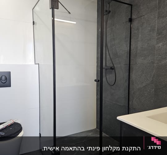 מקלחון זכוכית עם מסגרת שחורה וברז מקלחת